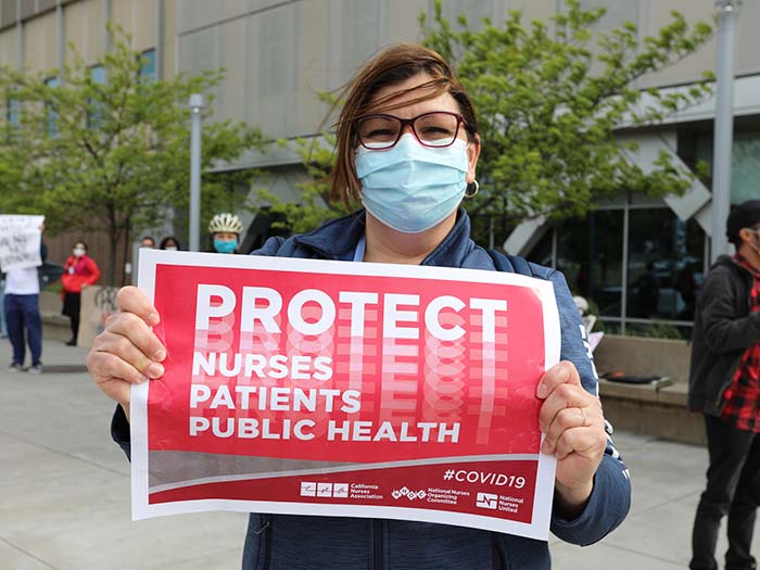Nurse holds sign "Protect nurses, patients, public health"