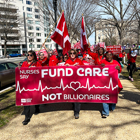Nurses marching holding banner "Fund Care Not Billionaires"