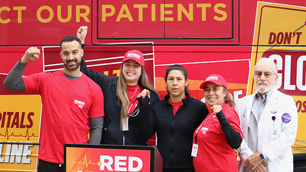 Five people in front of bus with raised fists