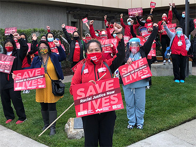 Large group of nurses outside with raised fists