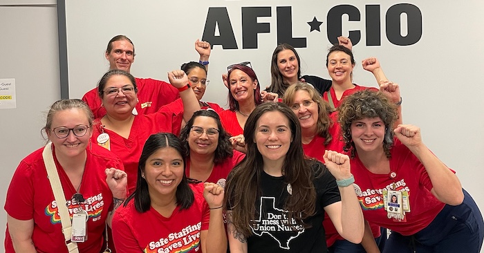 Nurses with raised fists, smiling, in front of wall "AFL*CIO"