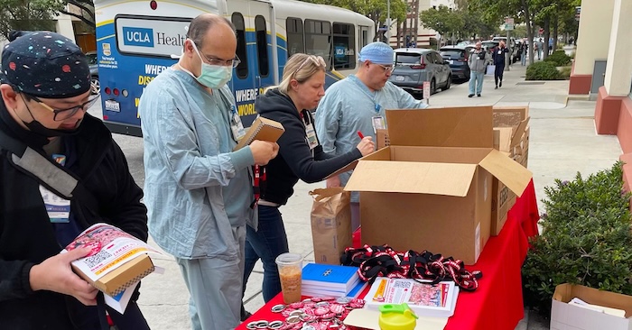 Four nurses setting up informational table outside of hospital