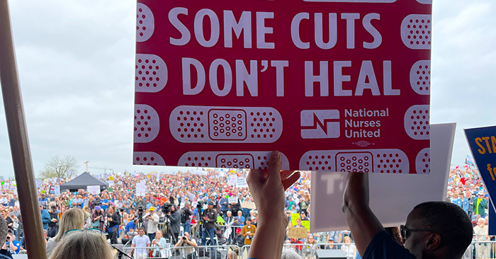 Hand holding sign "Some Cuts Don't Heal"