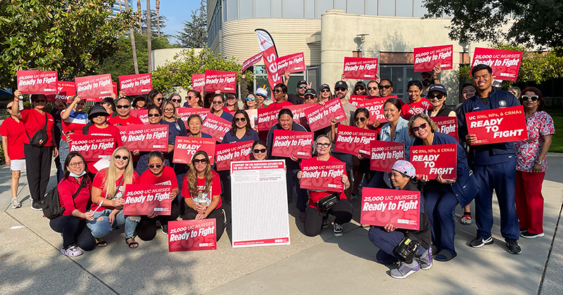 Large group of nurses outside holding signs "Ready to Fight"