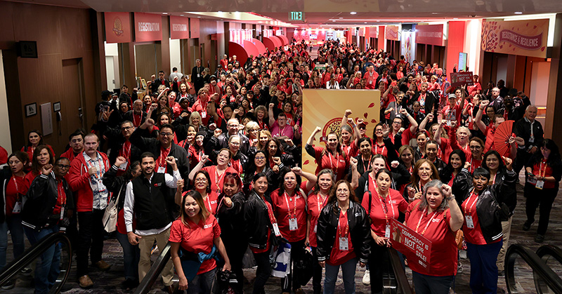 Large group of nurses in convention hall with raised fists