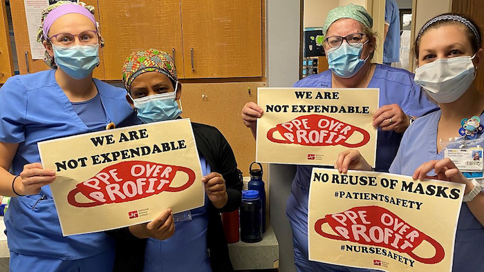 Nurses hold signs calling for PPE