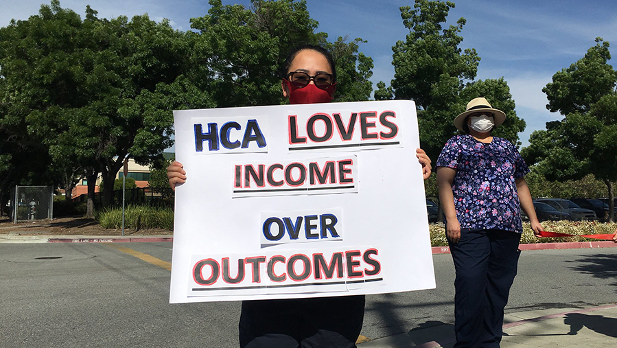 Nurses holds sign "HCA Loves Income Over Outcomes"