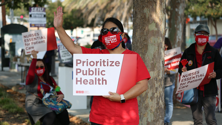 Nurse holds sign "Prioritize Public Health"