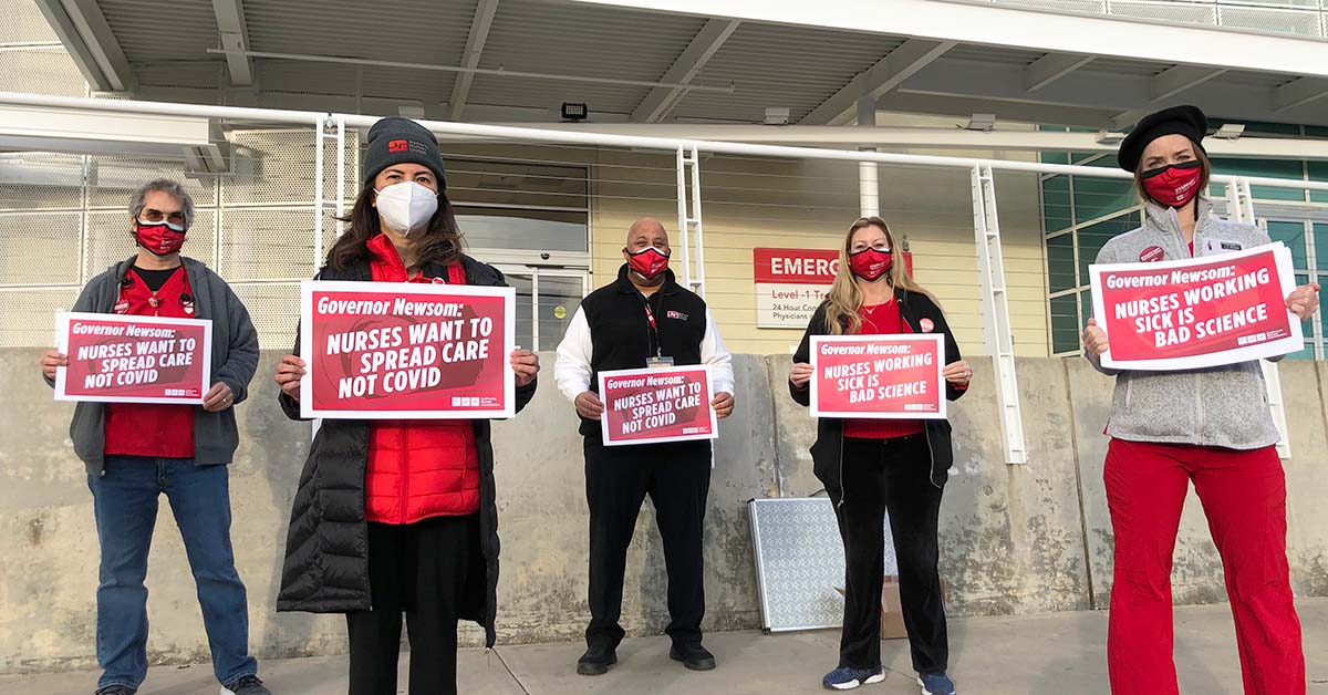 Nurses hold signs "Spread Care Not Covid"