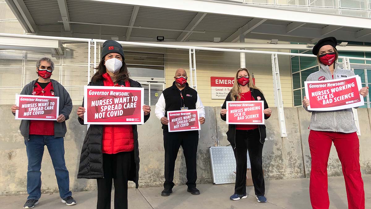 Nurses hold signs "Spread Care Not Covid"