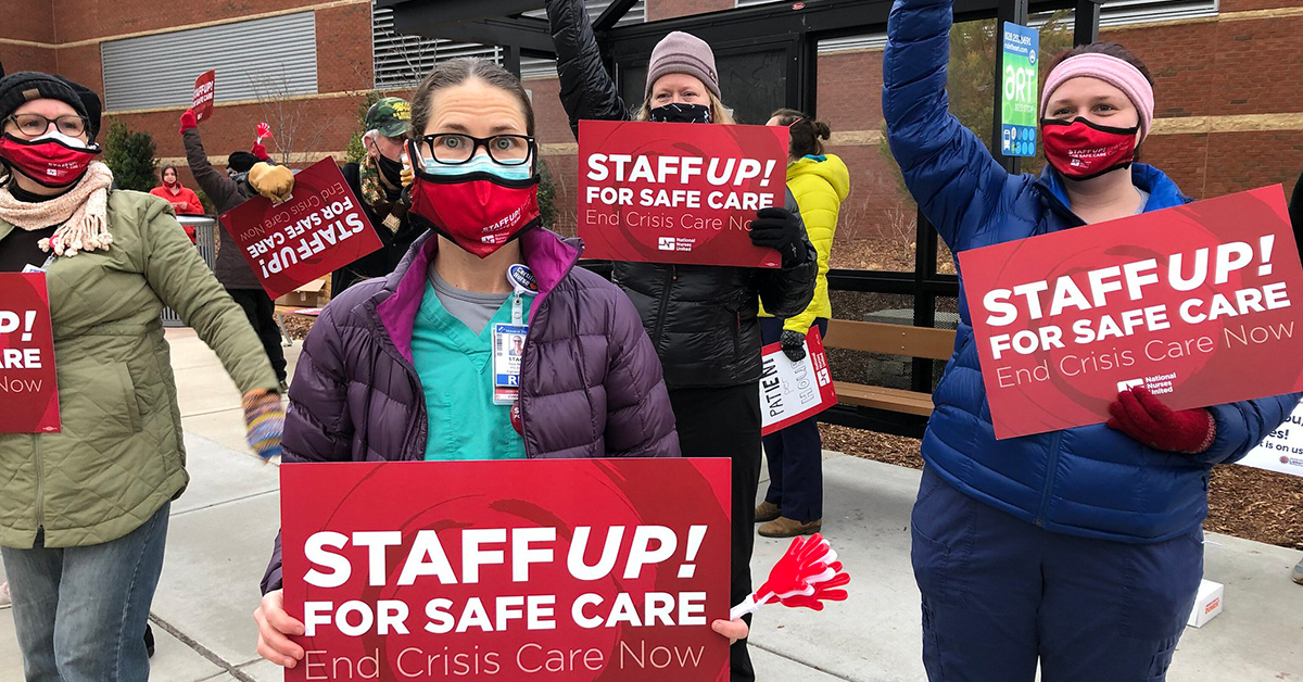 Group of four nurses outside hold signs "Staff up for safe patient care"