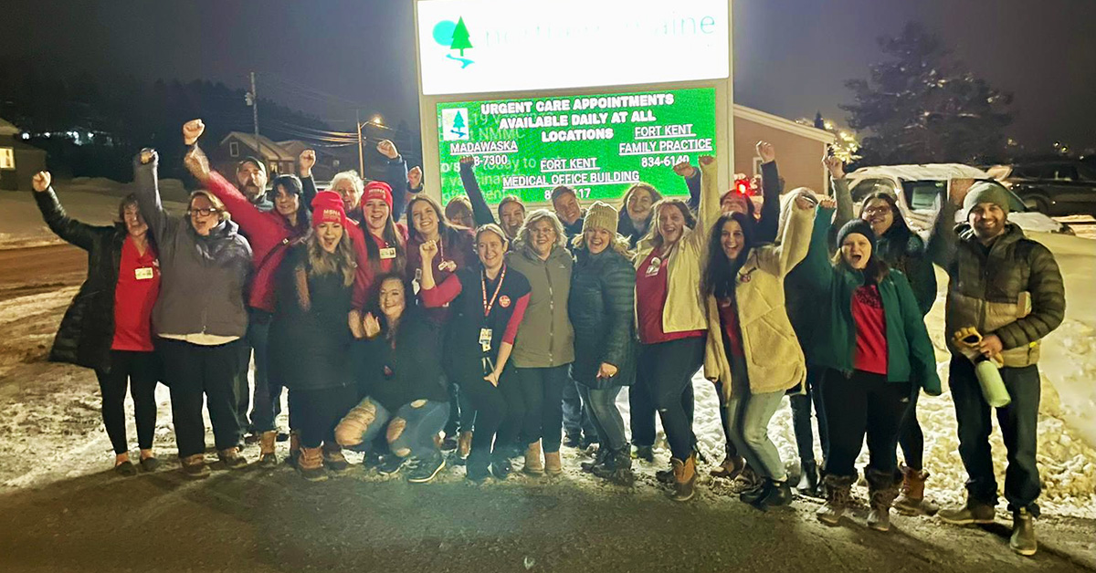 Large group of nurses standing outside hospital cheering with raised fists