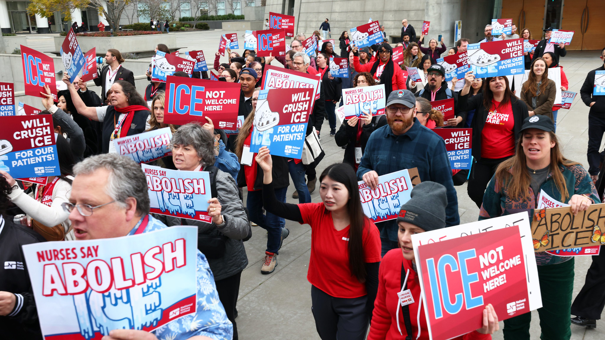Nurses marching holding signs "ICE Not Welcome Here"
