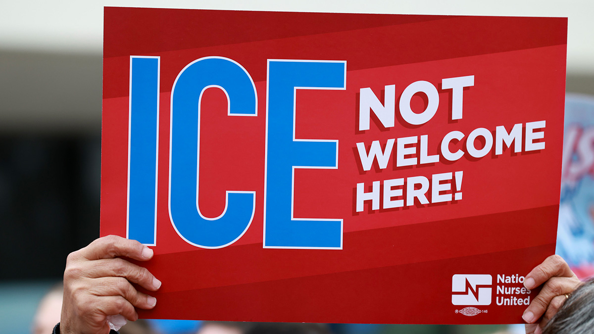 Hands holding sign "ICE Not Welcome Here"