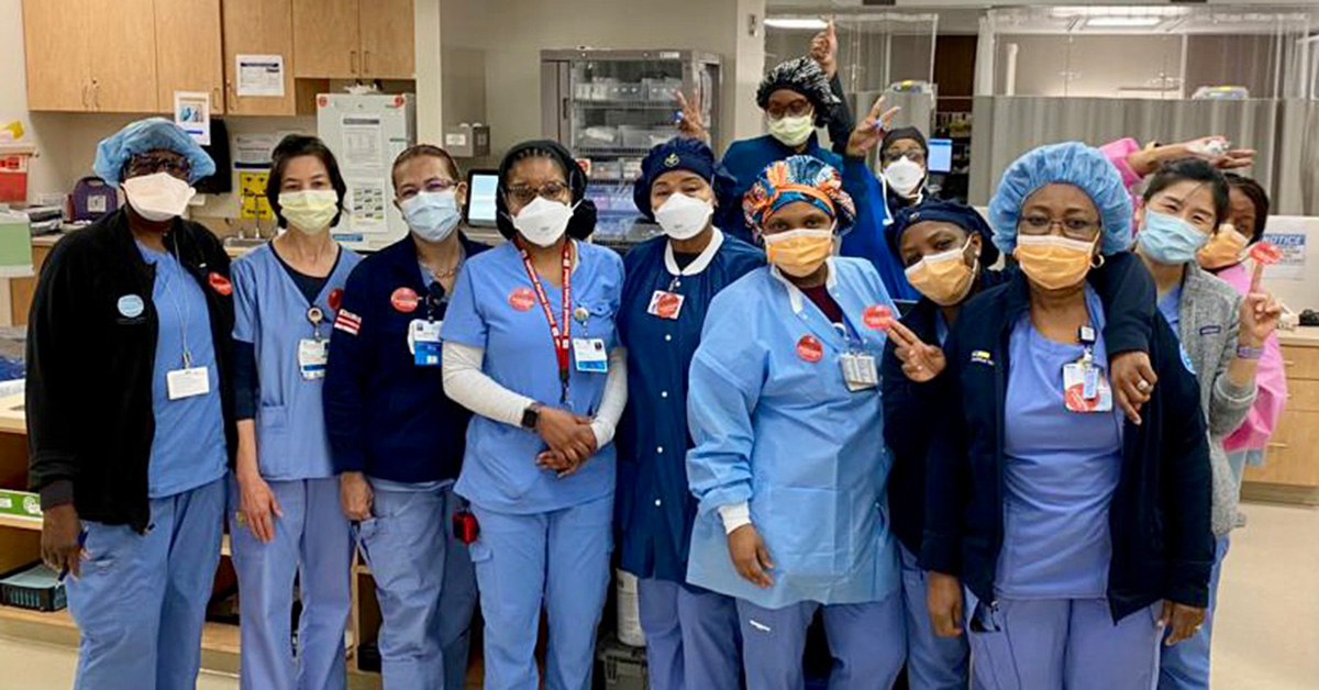 Group of nurses standing side-by-side, in hospital, smiling