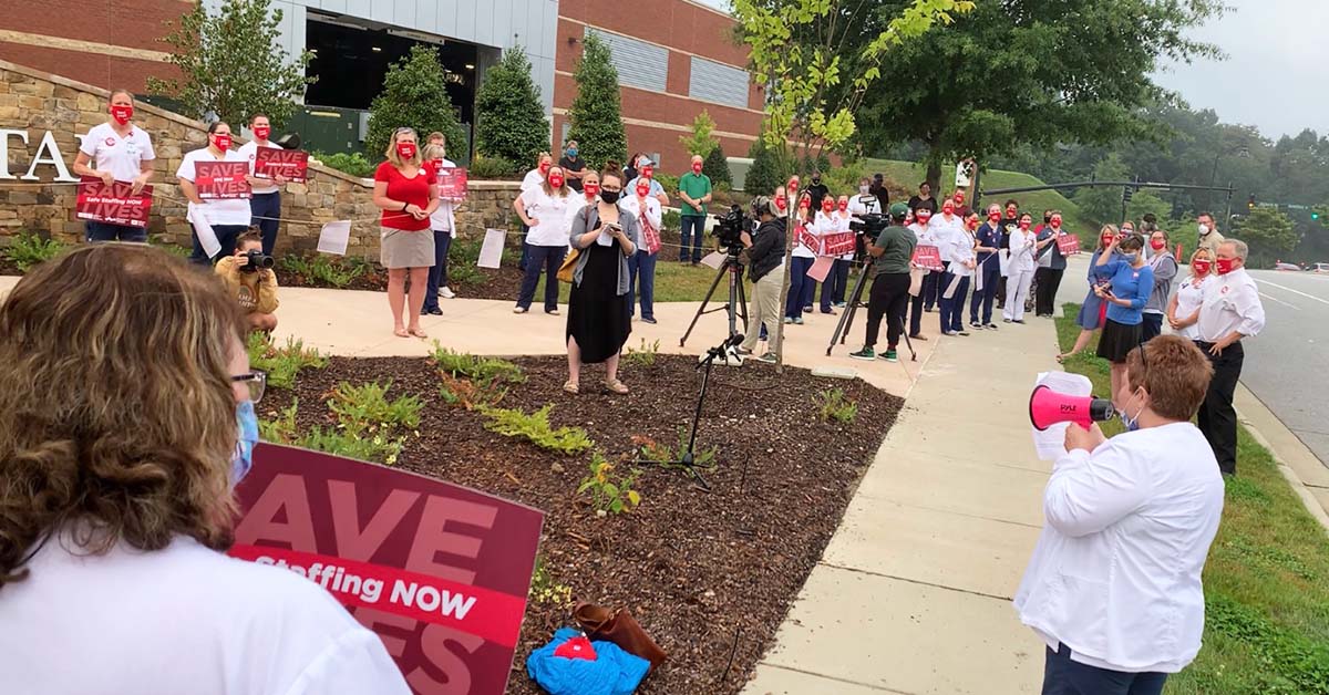 Group of nurses outside Mission Hospital, one speaking into megaphone