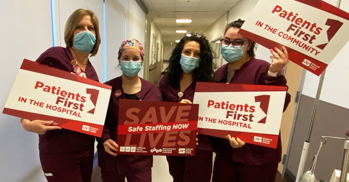 Four nurses holding signs in hospital hallway: "Patients First in the hospital" and "Save lives, safe staffng now"