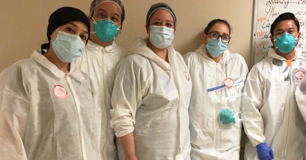 Group of five nurses inside hospital wearing protective gowns