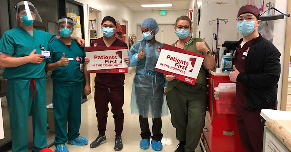 Nurses in hallway holding signs "Patients First in the Community" "Patients First in the Hospital"