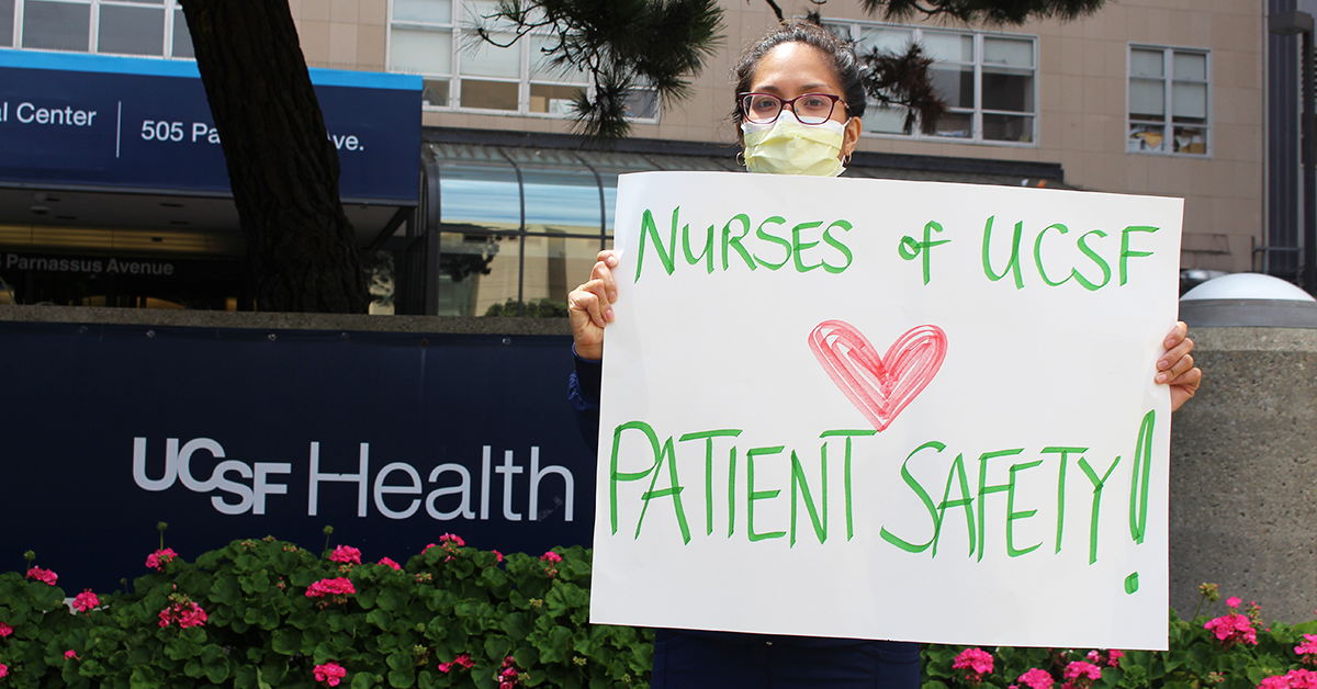 Nurse outside UCSF holding sign "Nurses of UCSF heart patient safety!"