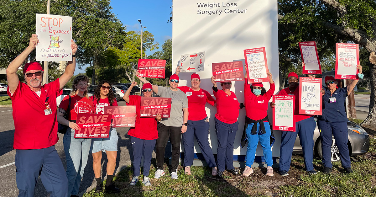 Large group of nurses outside HCA Florida Largo Hospital hold signs calling for safe staffing and other protections