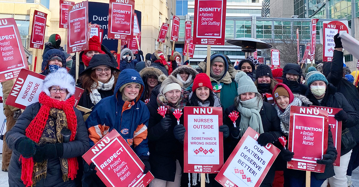 Large group of nurses outside UChicago in cold weather holding signs calling for dignity and respect