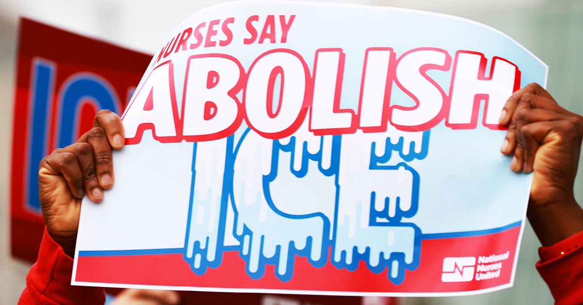 Nurse holding sign "Nurses say: Abolish ICE"