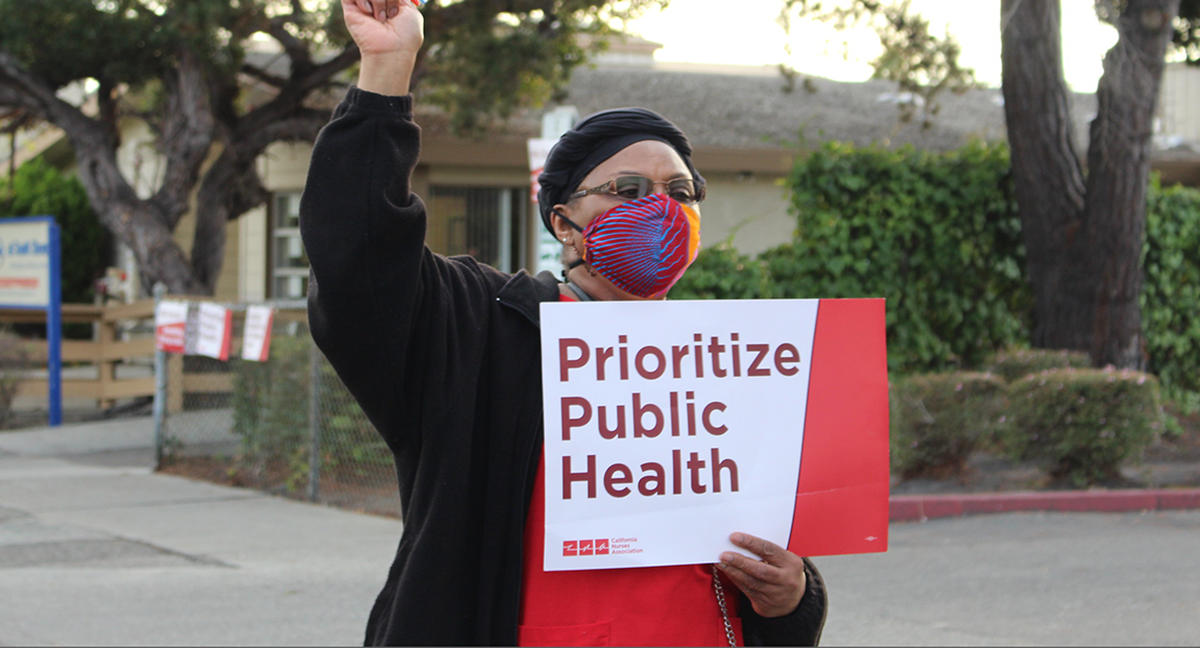 Nurse holds signs "Prioritize Public Health"