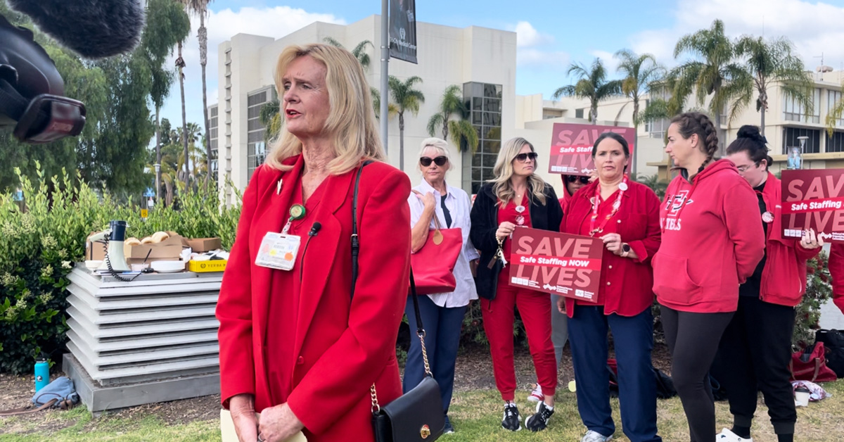 Nurse stands in front of TV camera, others stand behind 