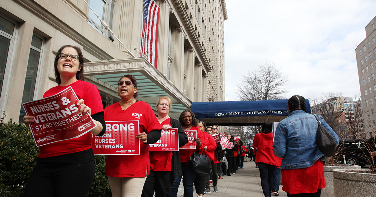 Nurses outside VA office hold signs "Nurses and Veterans Stand Together"