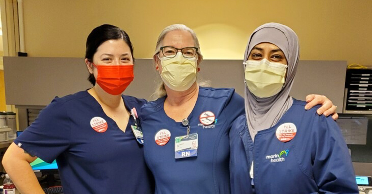 Three nurses inside hospital with arms around each other