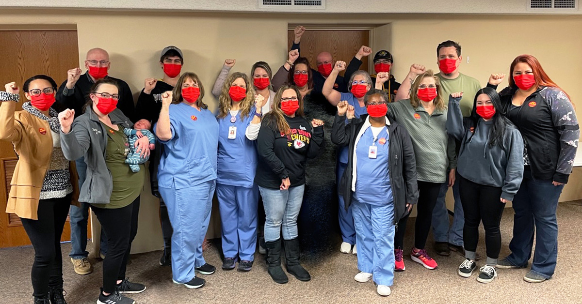 Large group of nurses inside hospital with raised fists