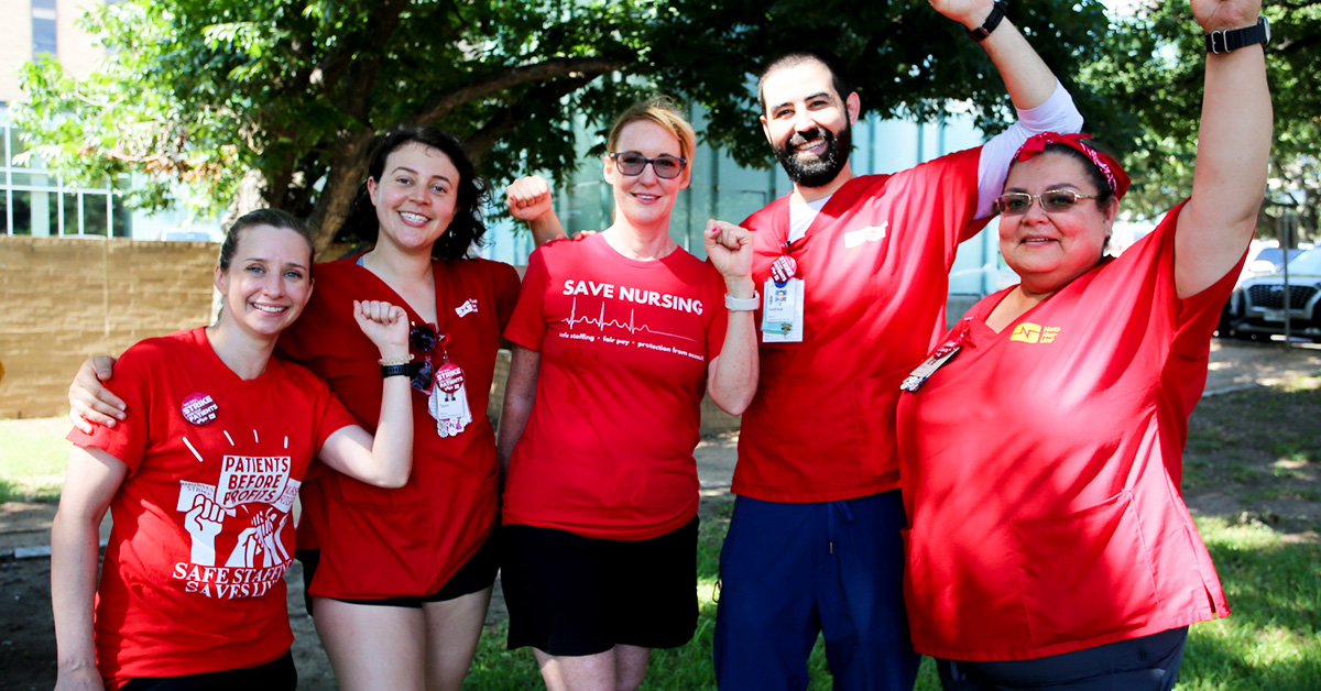 Five nurses standing next to each other smiling and with raised fists