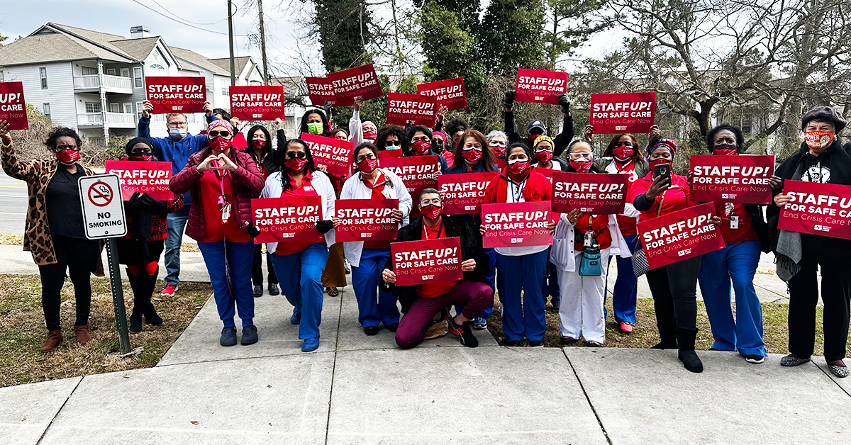 Group of Atlanta VA nurses holding signs "Staff up for safe care! End crisis care now!"