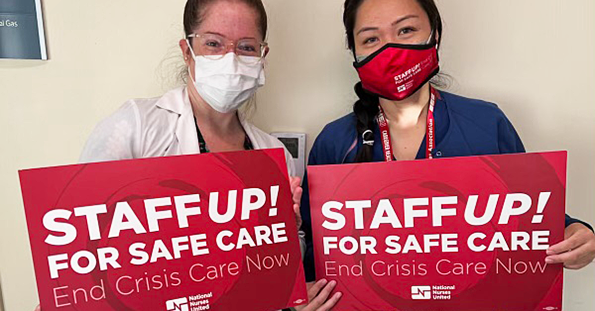 Two City of Hope medical staff holding signs "Staff up! For safe care. End Crisis Care Now"