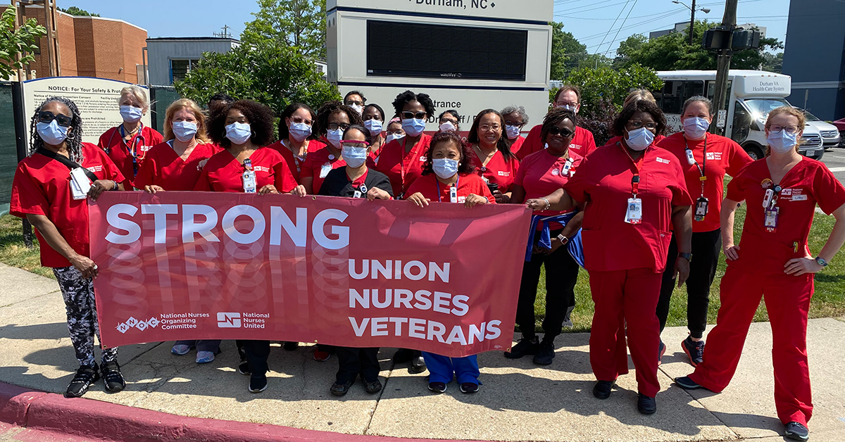 Large group of nurses outside hospital holding banner "Strong Union, Nurses, Veterans"