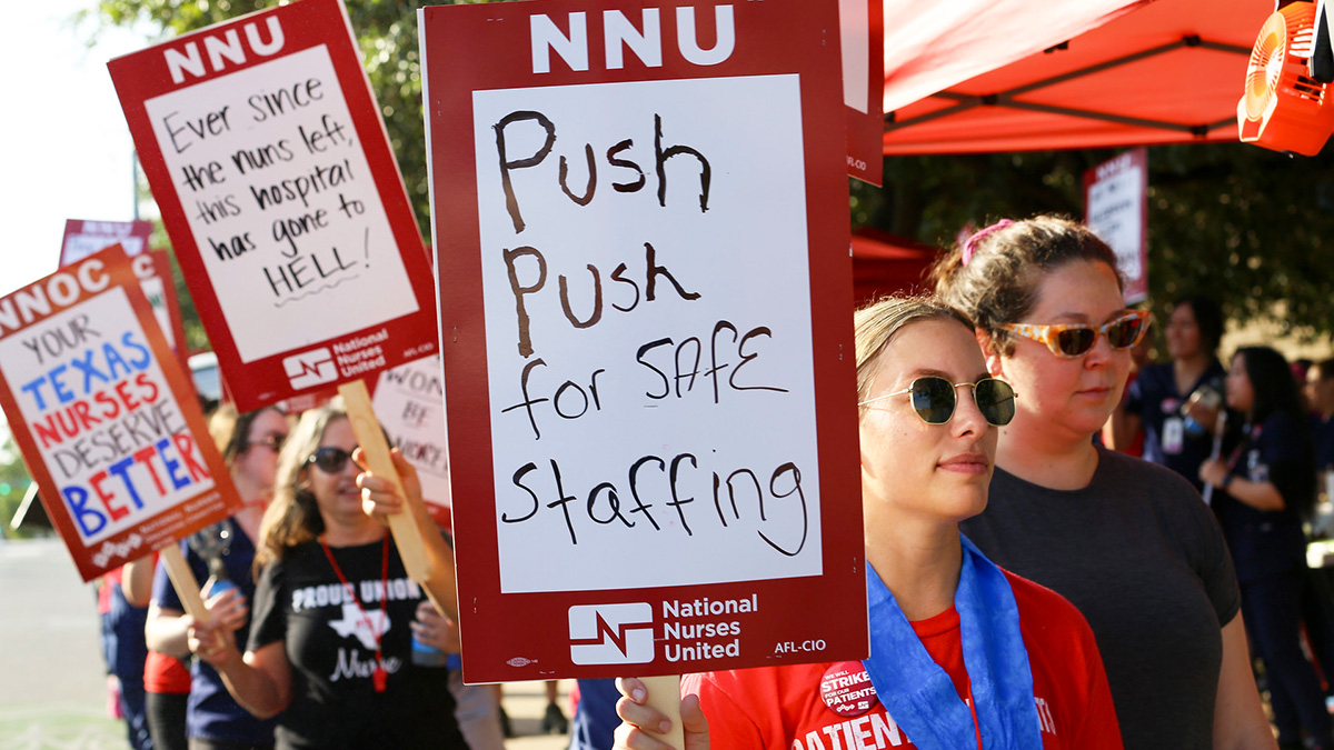 Nurse on picket line holds sign "Push Push for Safe Staffing"