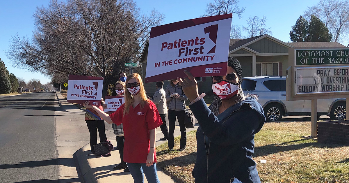 Group of four nurses outside Longmont Hospital hold signs "Patients First"