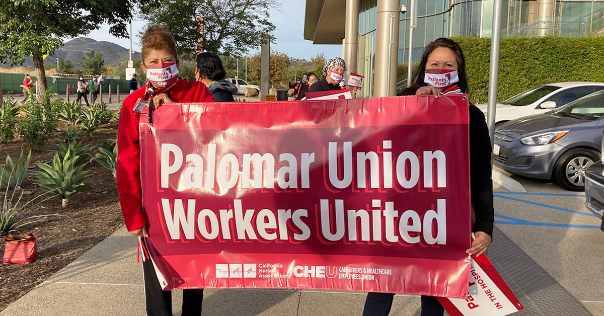 Two people outside hold sign "Palomar Union Workers United"