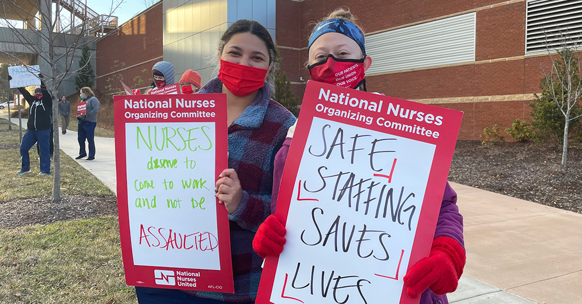 Two nurses outside holding signs calling for safe staffing and workplace violence prevention