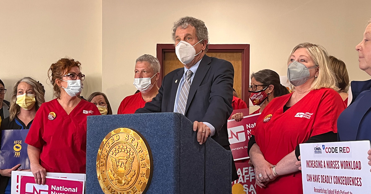 U.S. Senator Sherrod Brown at podium with nurses by his side