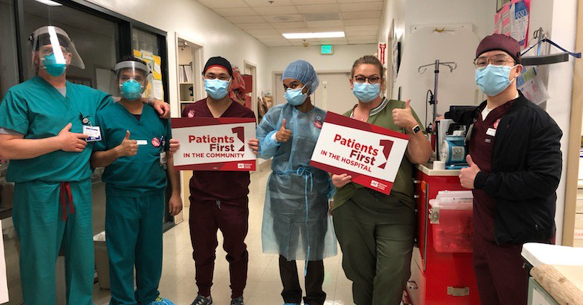 Group of nurses inside hospital hold signs "Patients First in the Hospital"