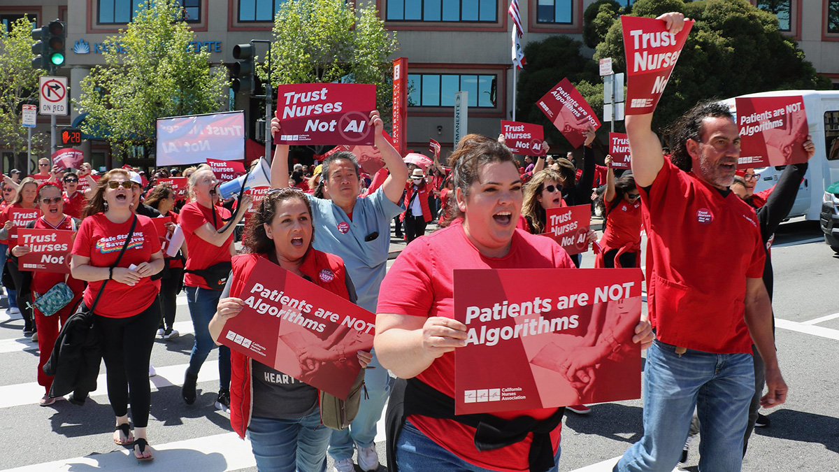 Nurses marching holding signs "Trust Nurses, Not AI" and "Patients Are Not Algorithms"