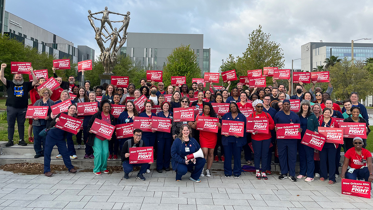 Large group of nurses outside smiling and holding signs "New Orleans RNs Ready to Fight"