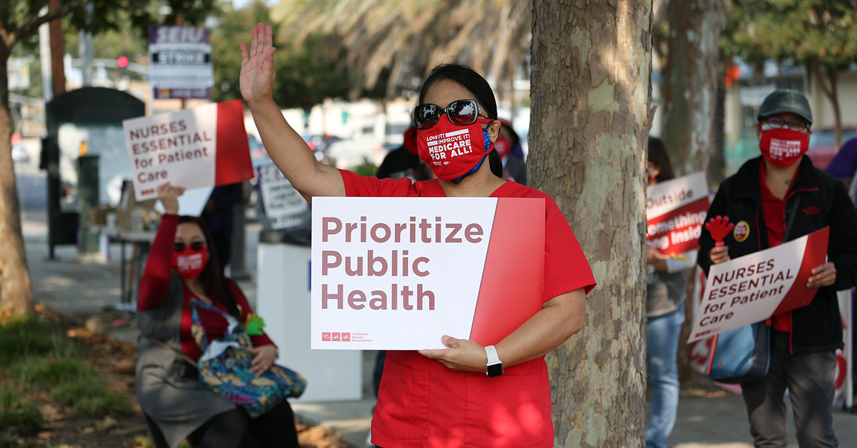 Nurse holds signs "Prioritize Public Health"