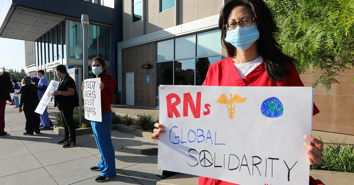 Nurse holds signs "RNs Global Solidarity"