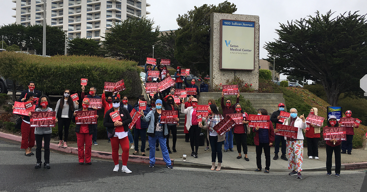 RNs on the street in front of hospital holding signs "Save Lives'