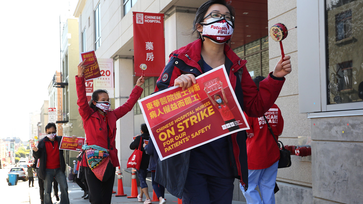Nurse on picket line hold sign "Chinese Hospital Nurses On Strike for Our Patient's Safety"
