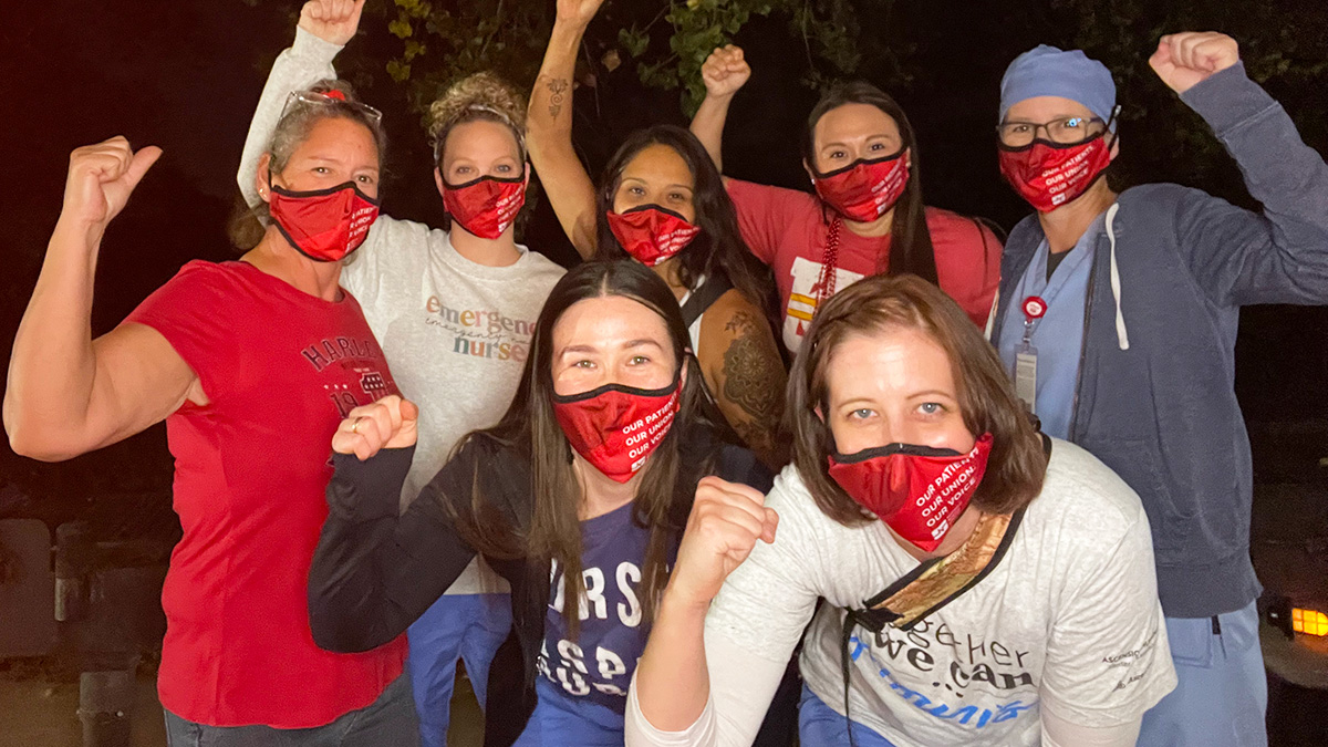 Group of nurses outside with raised fists