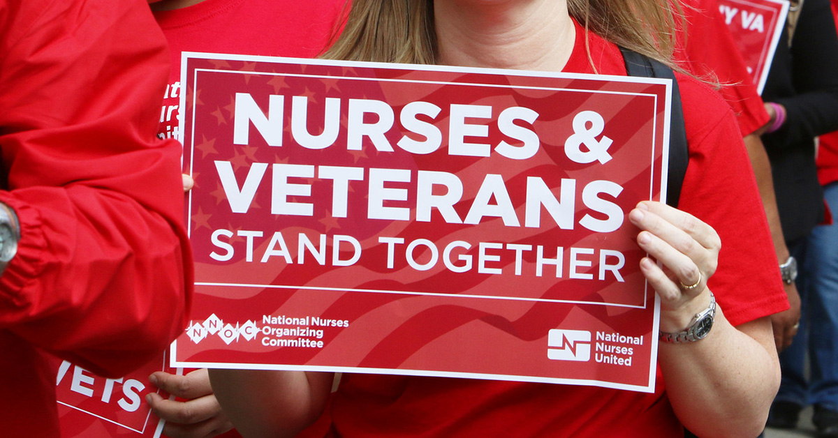 Nurse holds sign "Nurses & Veterans Stand Together"